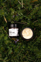 Two containers of tallow on a grassy background