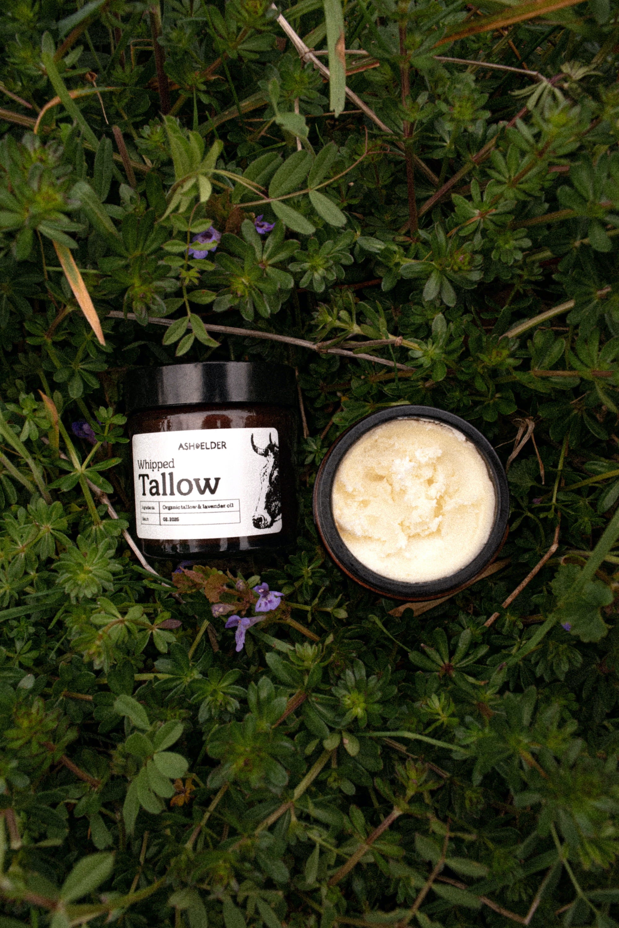 Two containers of tallow on a grassy background